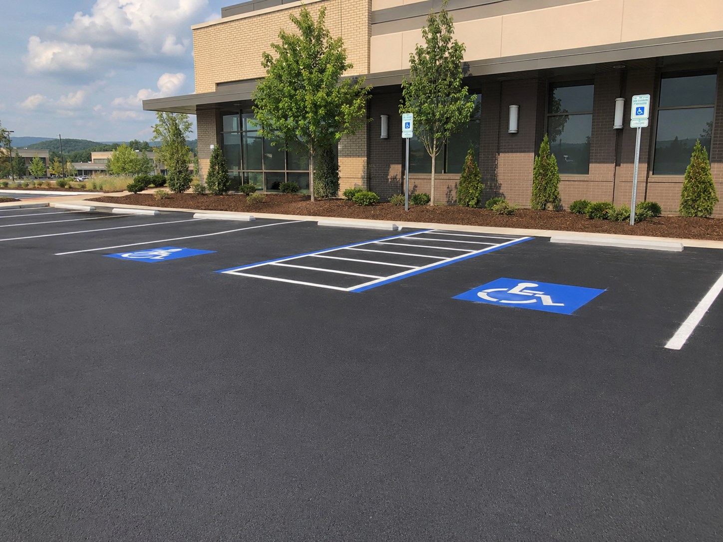 ADA accessible parking stalls with blue wheelchair symbols and van-accessible access aisle at commercial office building in Huntsville AL